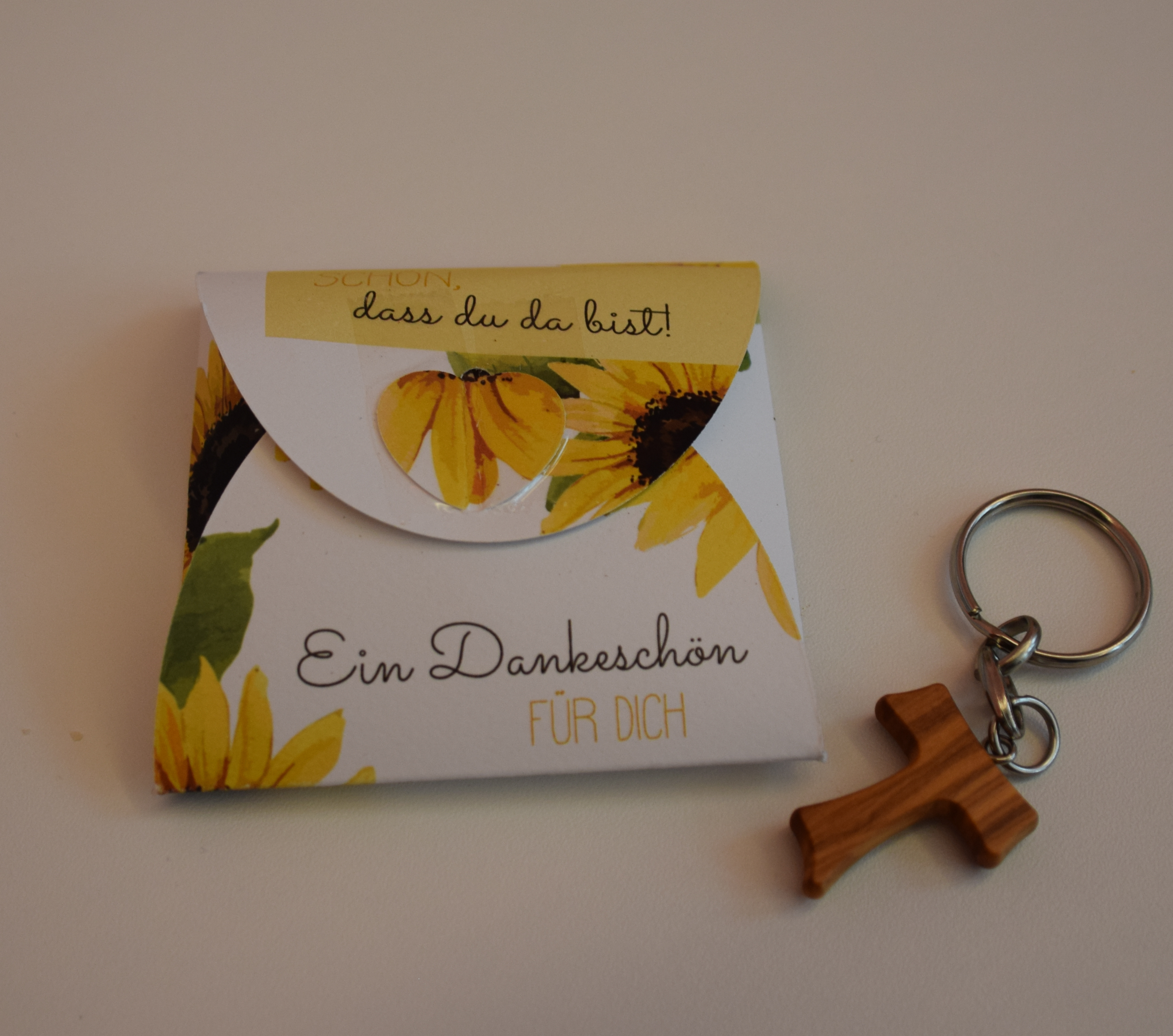 Taukreuz-Schlüsselanhänger und Blumensamen mit Pflanzherz für alle Mitarbeitenden 